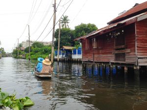 Unique views of Bangkok on the Chao Phraya River. Two ladies in a boat and houses on stilts